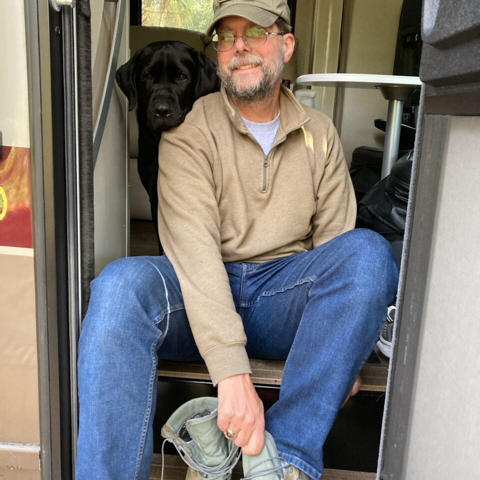 person and black lab in camper